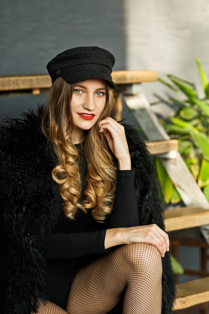 Portrait of attractive woman in a black cap and a coat with a fur collar