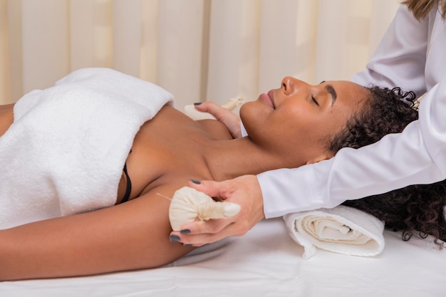 Photo portrait of attractive woman enjoying aromatic massage with pinda on arms and shoulders