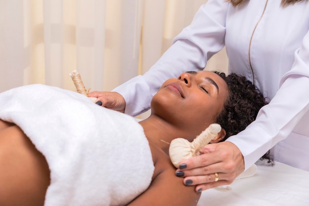 Portrait of attractive woman enjoying aromatic massage with pinda on arms and shoulders