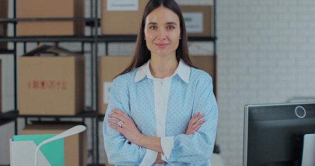 Portrait of an attractive woman looking at the camera crossing her arms The owner of a successful business works in a warehouse in an online store