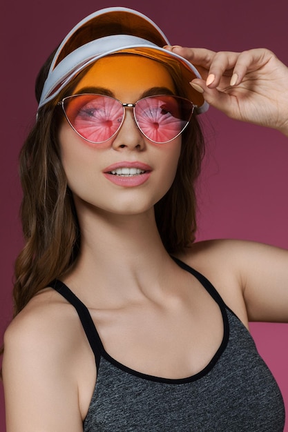 Portrait of attractive woman in orange sun visor and sunglasses