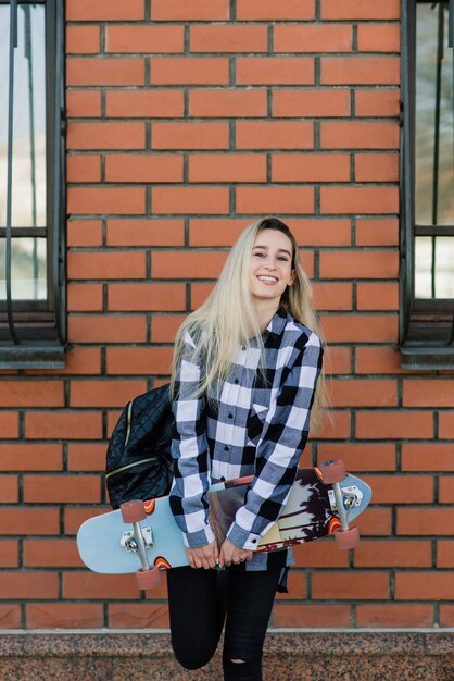 Portrait of attractive woman in sunglasses smiling standing with longboard