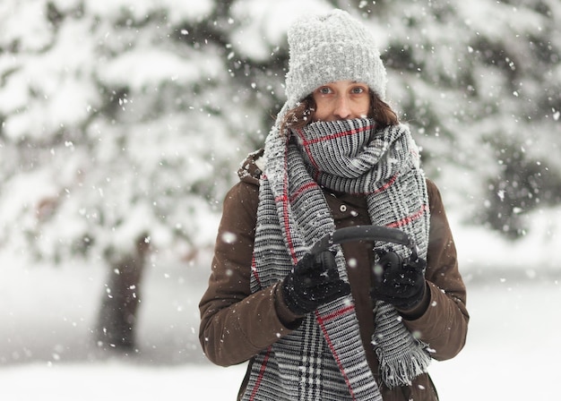 Portrait of attractive woman in warm clothes in winter snowy weather outdoors