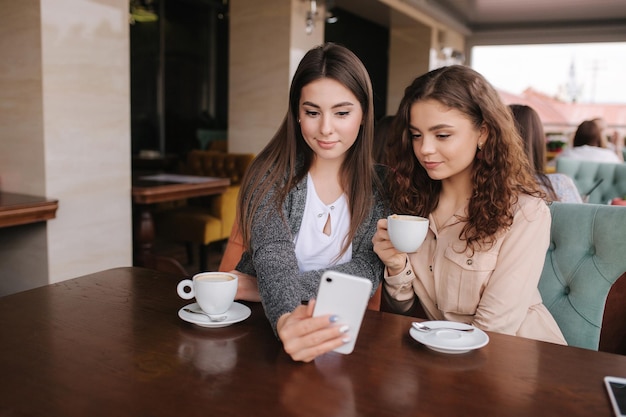 魅力的な女性の肖像画は、カフェで電話を見てください。