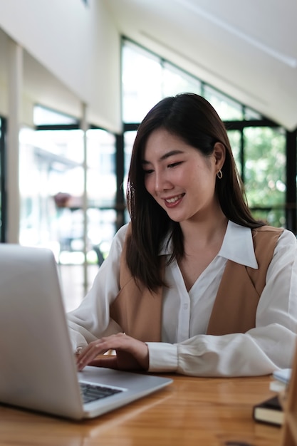 Portrait of an attractive young Asian woman is working on laptop at the office