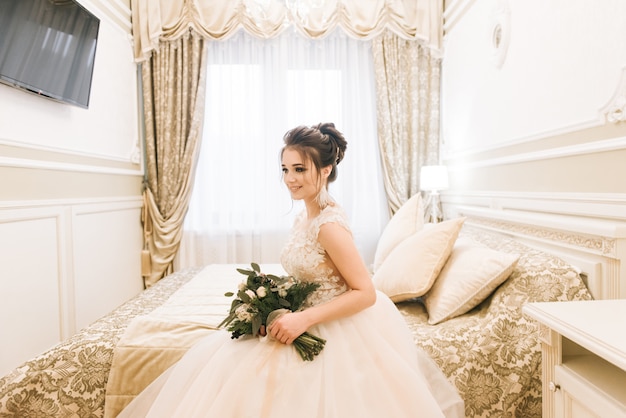 Portrait of an attractive young bride with a winter bouquet. Morning bride in a luxury hotel