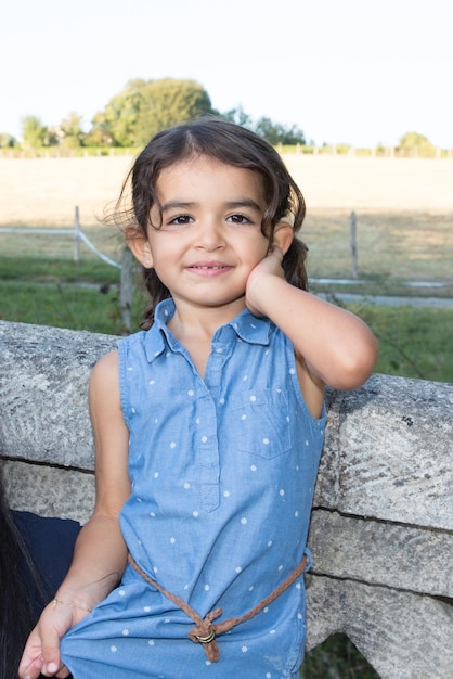 Portrait of attractive young brunette smiling child girl with long hair in blue dress