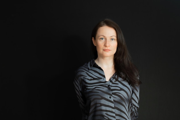 Portrait of an attractive young business woman looking at the\
camera isolated on a black background