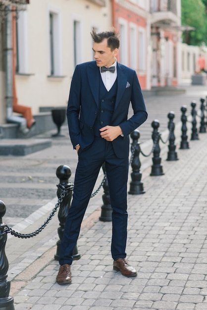 スーツとネクタイを身に着けている都市通りで魅力的な青年実業家の肖像画。