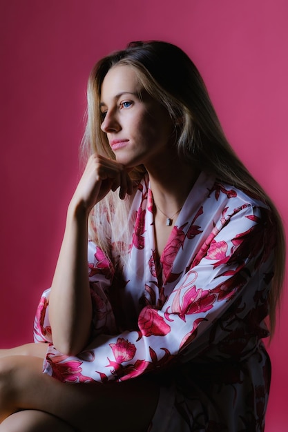 Portrait of an attractive young Caucasian female posing against a pink wall
