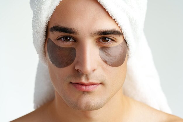 Portrait of attractive young male model with eye patches on white background