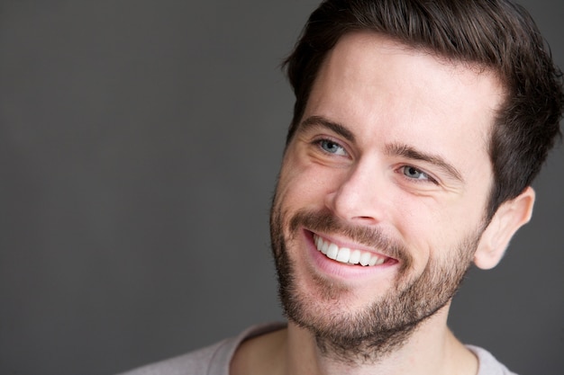 Portrait of an attractive young man smiling on gray background