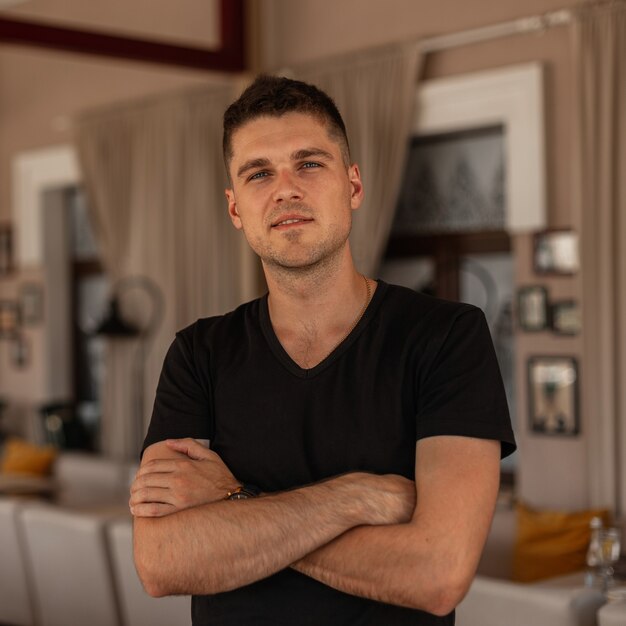 portrait of an attractive young man with a stylish hairstyle in a fashionable black t-shirt indoors.