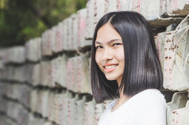 柱の前で笑顔で立っている魅力的な若い賢い女性の肖像画