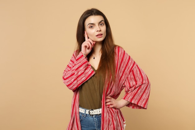 Portrait of attractive young woman in casual clothes looking camera, put hand prop up on chin isolated on pastel beige wall background. People sincere emotions, lifestyle concept. Mock up copy space.