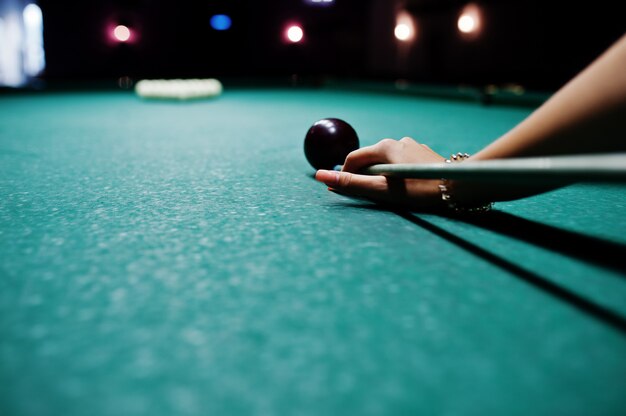 Portrait of an attractive young woman in dress playing pool.