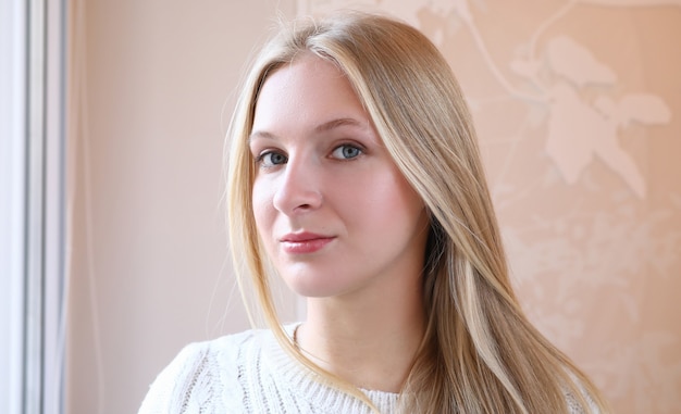 Portrait of attractive young woman smiling and wearing white knitted sweater