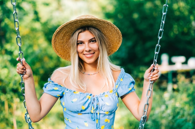 Portrait of attractive young woman in straw hat outdoors in summer sunny day.