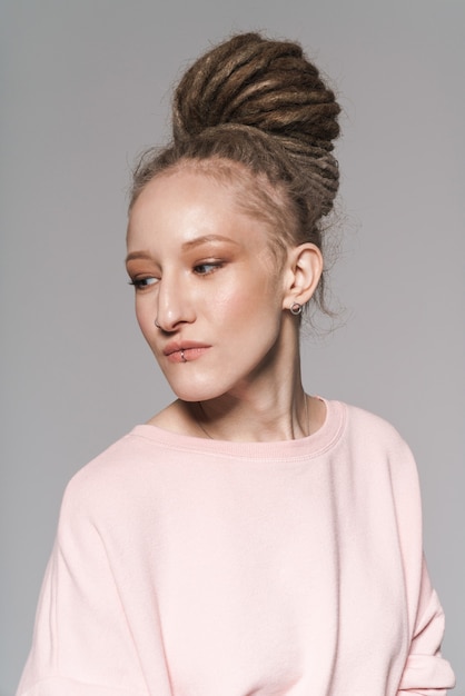 Portrait of an attractive young woman with dreadlocks standing isolated, posing, looking away