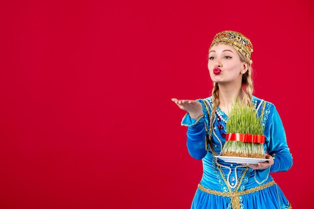 Portrait of azeri woman in traditional dress with green semeni on red background concept ethnic novruz dancers spring