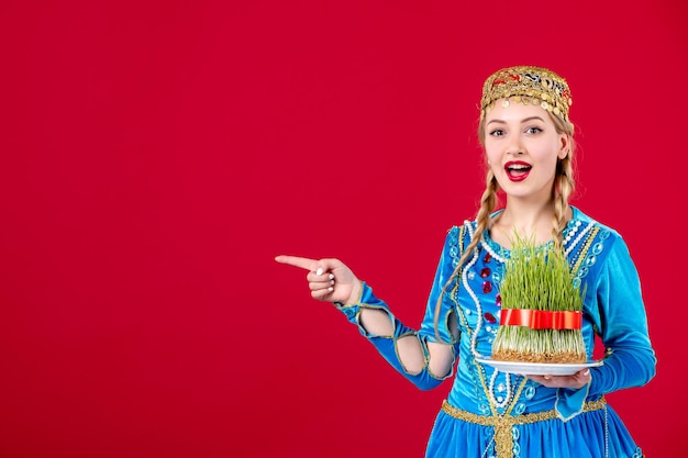 Portrait of azeri woman in traditional dress with green semeni on red background ethnic spring concept novruz colors