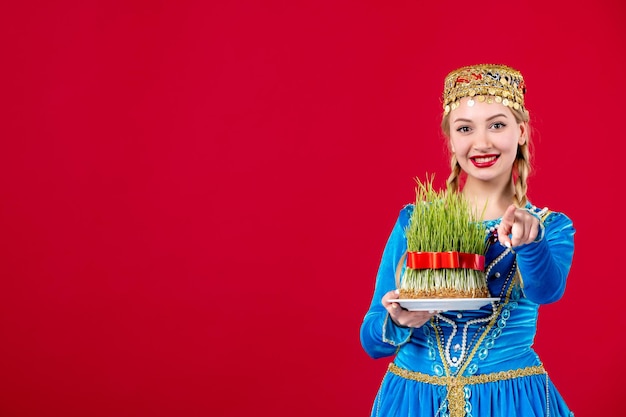 Portrait of azeri woman in traditional dress with green semeni on red background novruz ethnic concept dancer