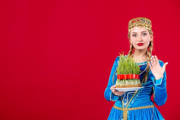 Portrait of azeri woman in traditional dress with green semeni on red background novruz ethnic concept spring dancers