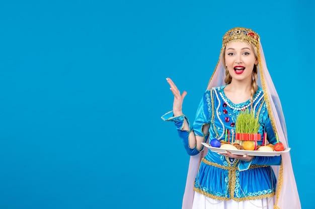 Portrait of azeri woman in traditional dress with xonca on blue background novruz ethnic dancer concept