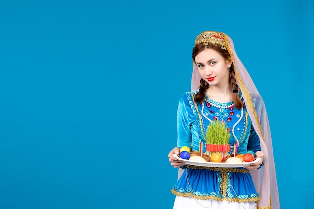 Photo portrait of azeri woman in traditional dress with xonca blue wall novruz spring ethnic dancers
