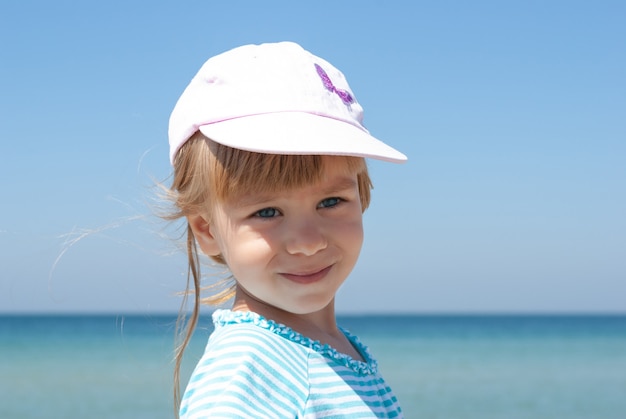 紺碧の海に対して帽子をかぶった女の赤ちゃんの肖像画