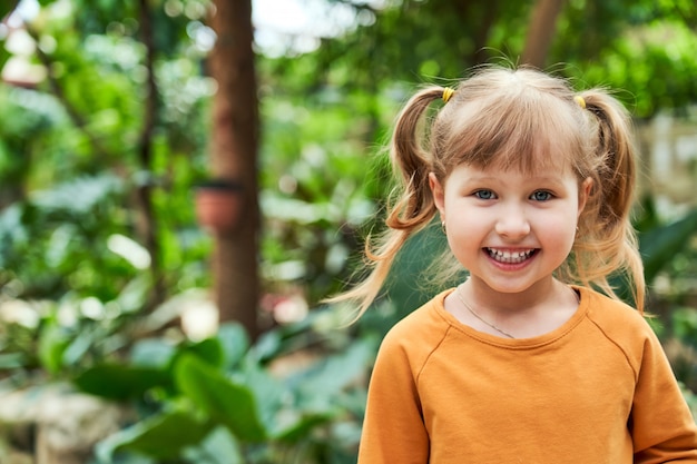 Portrait of a baby girl in the jungle. cheerful child in the zoo.