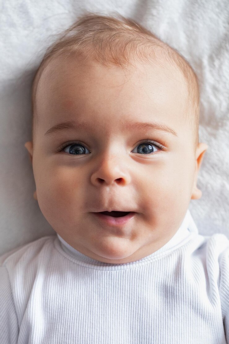Portrait baby little cheerful boy on a white blanket closeup