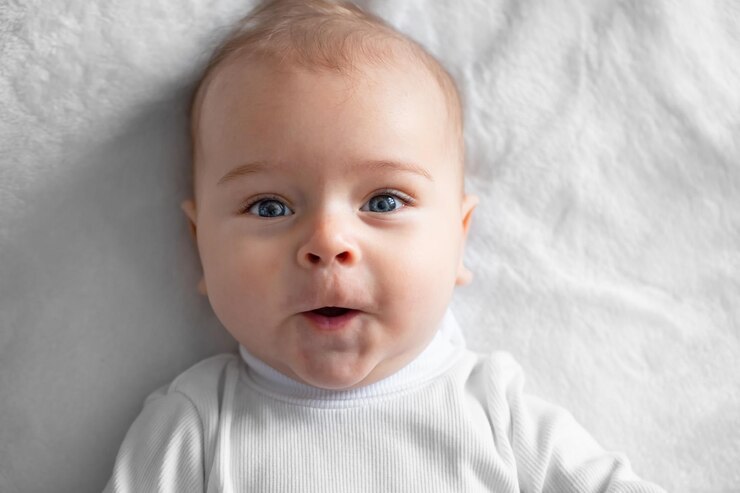 Portrait baby little cheerful boy on a white blanket closeup
