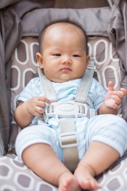 portrait of baby sit on stroller carriage in park