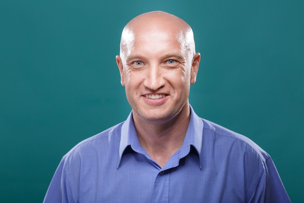 Photo portrait of a bald man on a blue background model in her s blue eyes and a blue shirt  smiling facia...