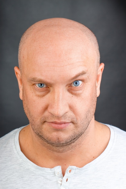 Портрет лысого мужчины с голубыми глазами крупным планом