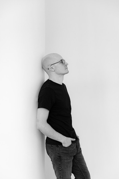 Portrait of a bald young man in a black tshirt with\
glasses