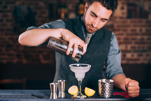 Photo portrait of barman pouring fresh lime margarita in fancy glass at restaurant