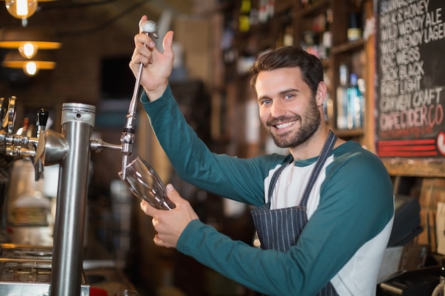 Ritratto del barista che versa birra dal rubinetto