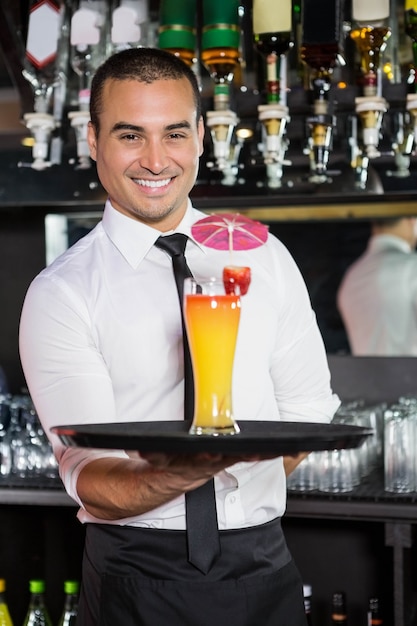 Портрет бармена, обслуживающего коктейль у барной стойки