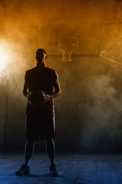 Photo portrait of a basketball player holding a ball in his hands in a gymnasium