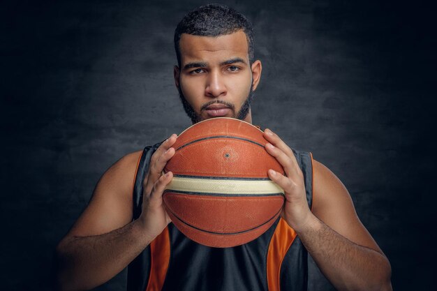 Il ritratto di un uomo di colore barbuto tiene una palla da basket.