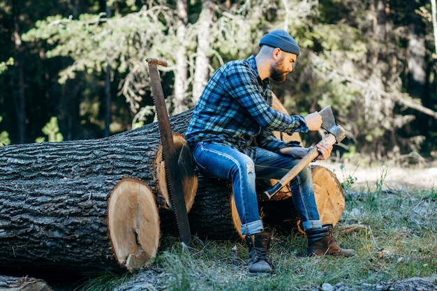 Photo portrait of a bearded brutal woodcutter holding ax in hand