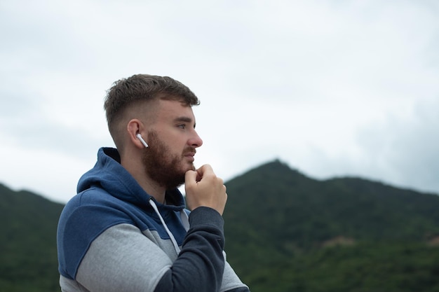 Photo portrait of bearded handsome pensive thoughtful guy listen music in earphones young upset sad