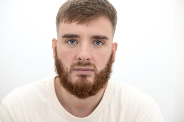 Portrait of bearded happy young handsome man with beard is smiling on white background and looking at camera