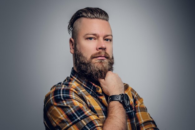 Photo portrait of a bearded hipster male with punk hairstyle dressed in a yellow shirt on grey background.