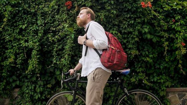 Portrait of bearded hipster man walking with vintage bicycle at park.