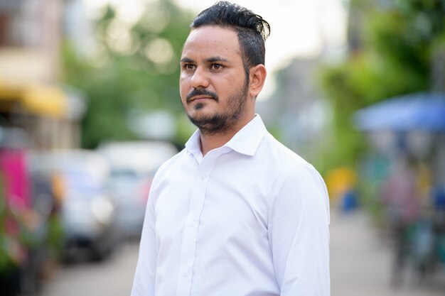 Portrait of bearded Indian businessman in the street outdoors