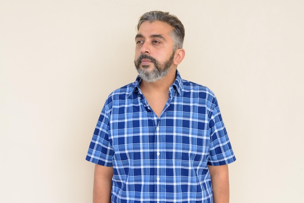 Ritratto di uomo d'affari indiano barbuto che pensa su sfondo semplice