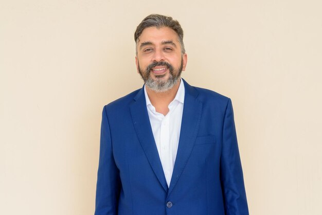 Portrait of bearded Indian businessman wearing suit against plain background